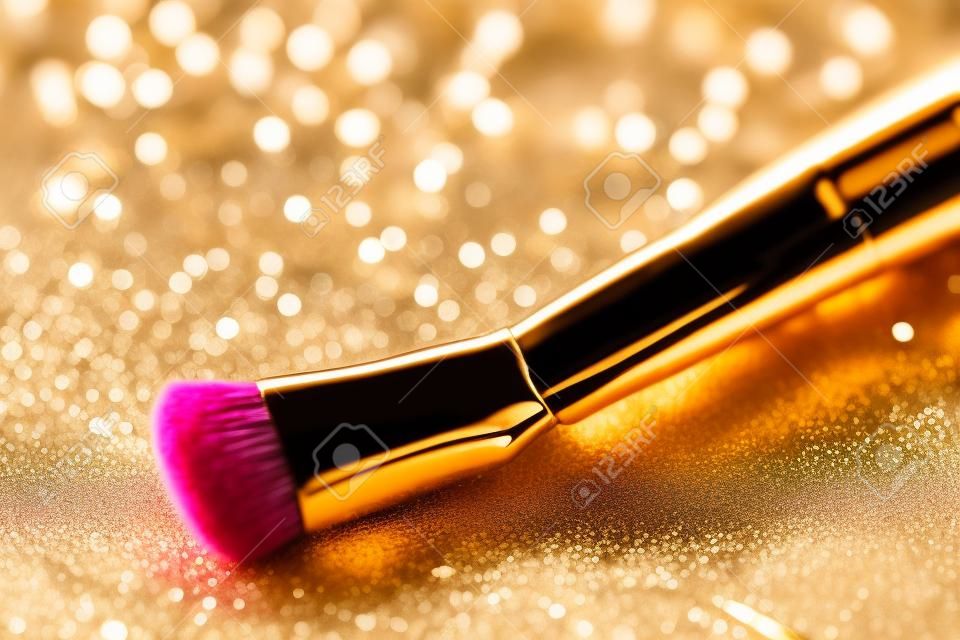 Close-up on makeup brush and gold shining powder