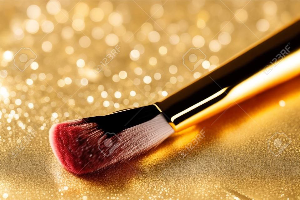 Close-up on makeup brush and gold shining powder