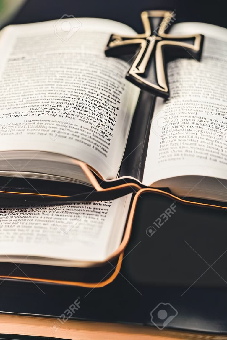 Uma Bíblia aberta é colocada em uma superfície de mesa preta. No centro das páginas abertas está uma cruz de Tao.