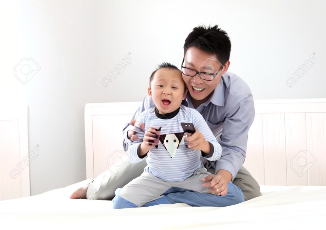 年輕的父親與他的兒子在床上的男孩玩，在家中，亞洲的生活方式