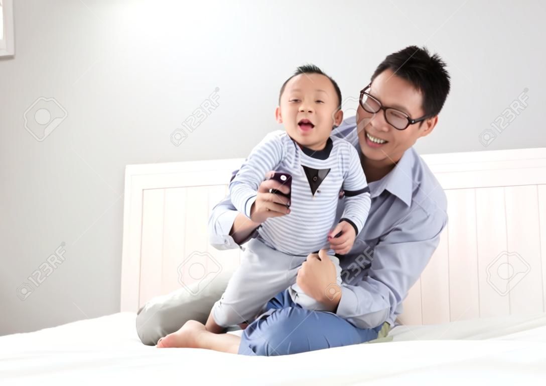 年輕的父親與他的兒子在床上的男孩玩，在家中，亞洲的生活方式