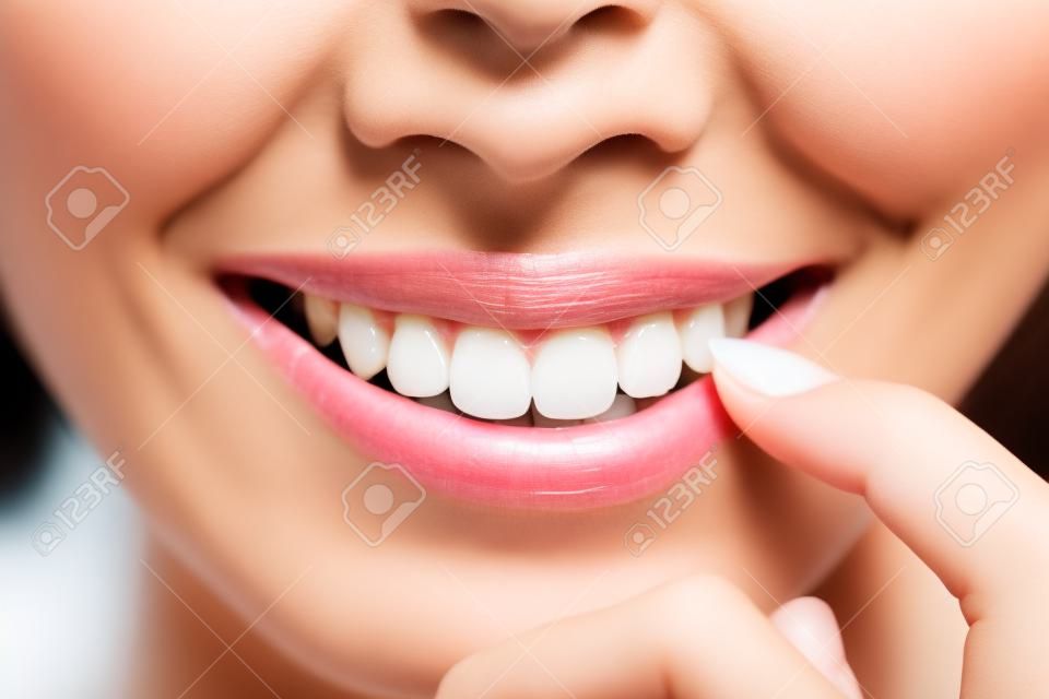 Gyönyörű fiatal nő egészségügyi fogak közelről és bájos mosollyal. Elszigetelt felett fehér ázsiai szépség