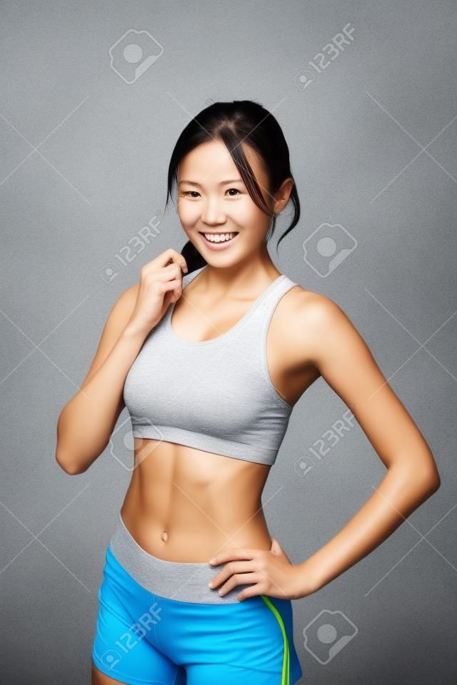 Sport Mädchen auf grauem Hintergrund. Laufen Fitness-Sport Frau lächelt glücklich. asiatische Schönheit