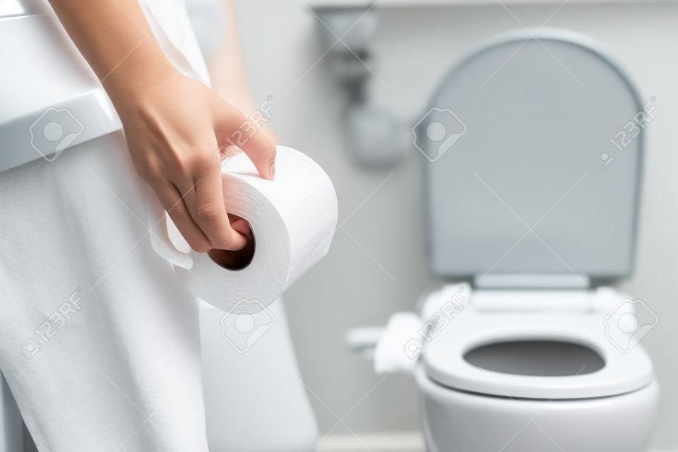 vrouw nemen toiletpapier in de badkamer