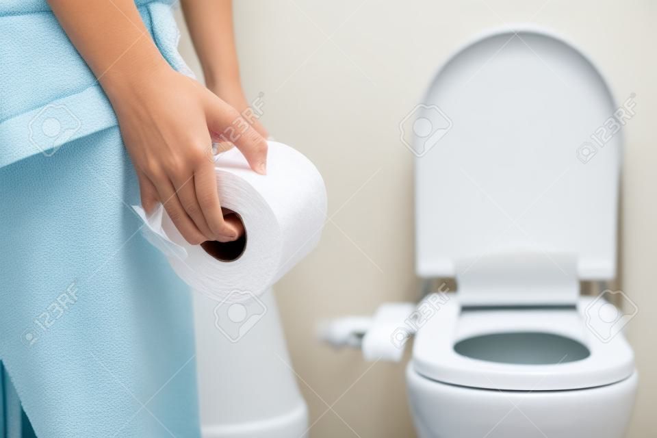 vrouw nemen toiletpapier in de badkamer