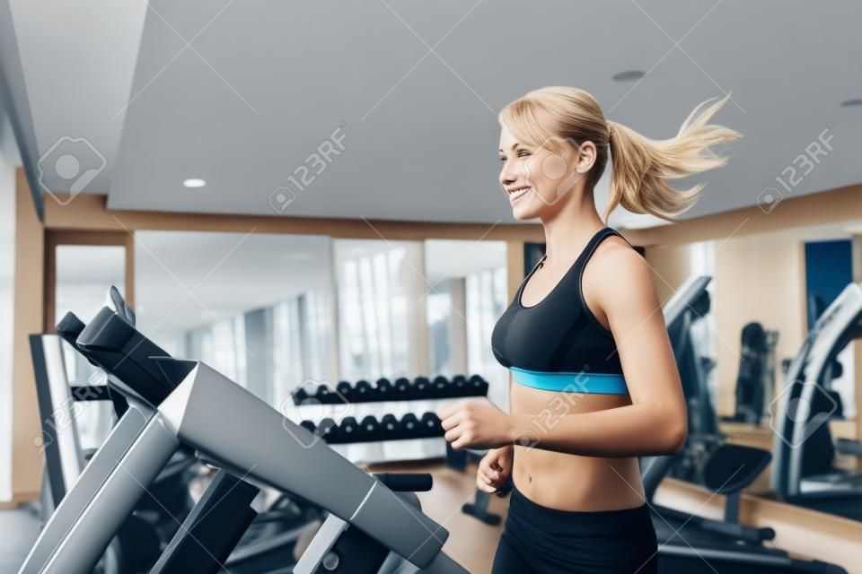 Kobieta biegnie na bieżni na siłowni