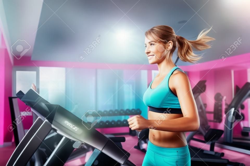 Kobieta biegnie na bieżni na siłowni