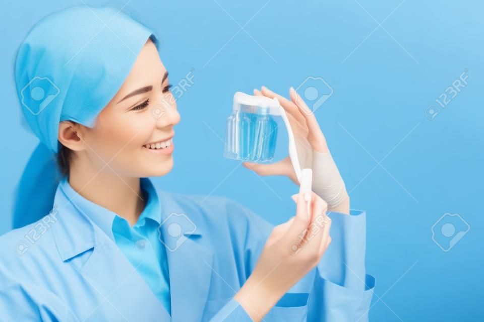 Zahnärztin nimmt Gesundheitszahn und Zahnbürste auf blauem Hintergrund