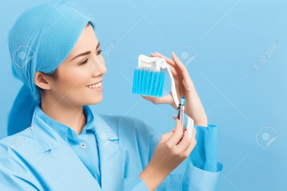 여자 치과 의사는 파란색 배경에 건강 치아와 치아 브러시를 가지고