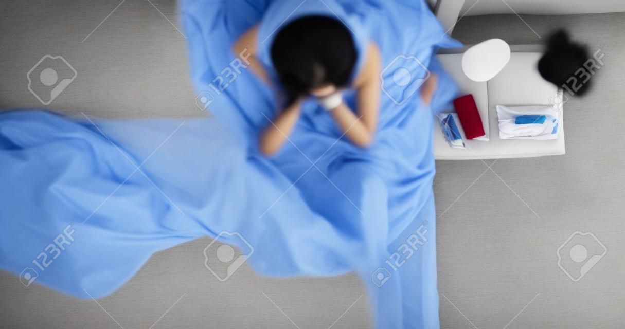 Vista aérea de la mujer asiática estaba triste y sentada en la cama