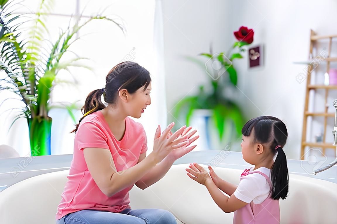 Mama bringt dem Kind bei, wie man sich die Hände richtig wäscht, um Covid-19 zu Hause zu vermeiden