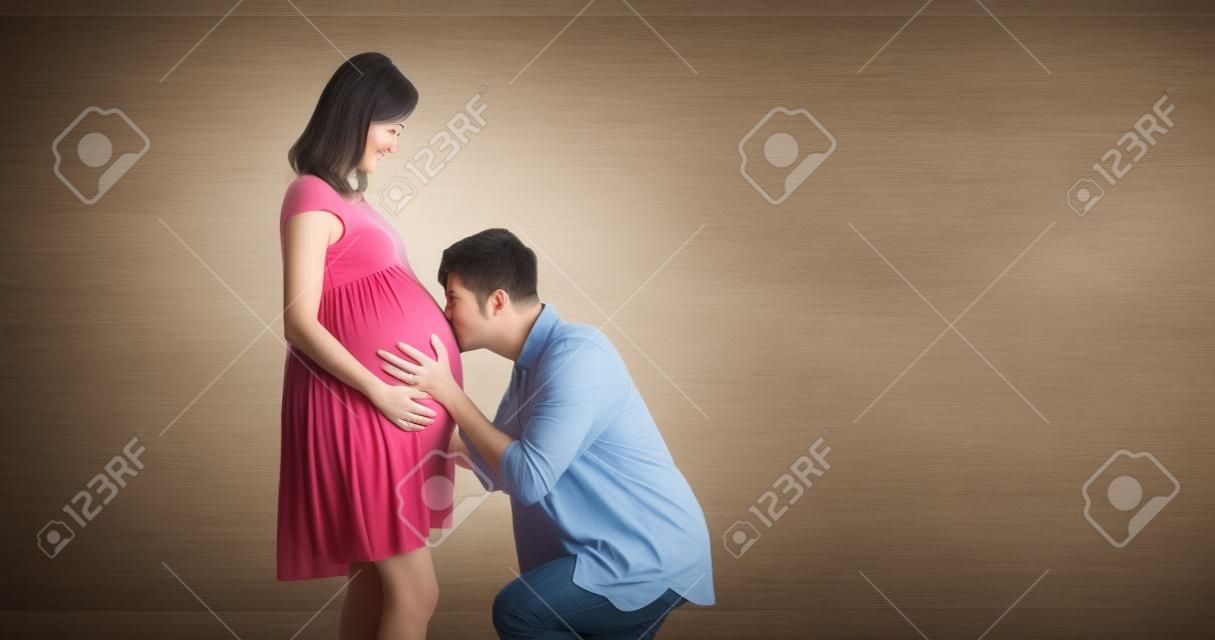 happy pregnant couple expecting baby and kiss the baby through the belly
