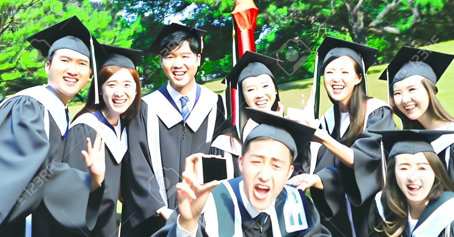 un groupe d'étudiants diplômés heureux utilise un téléphone portable pour prendre une photo ensemble
