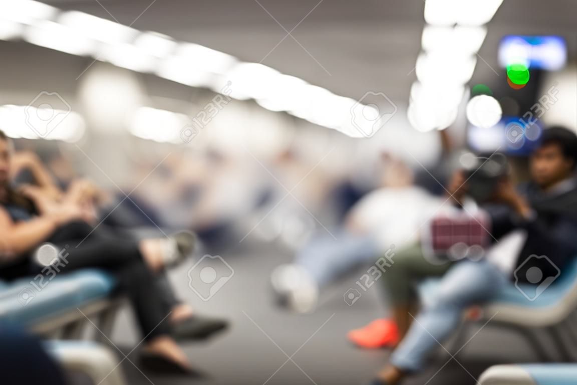 Pessoas embaçadas sentadas esperando no terminal da estação do aeroporto