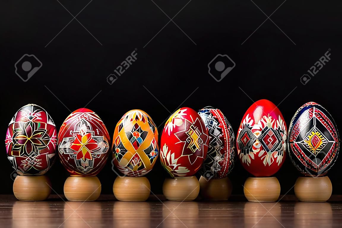 Pysankas in a row, decorated Easter eggs on black background.