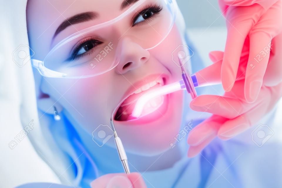 Nahaufnahmeporträt einer Patientin beim Zahnarzt in der Klinik. Zahnaufhellungsverfahren mit UV-Licht UV-Lampe.