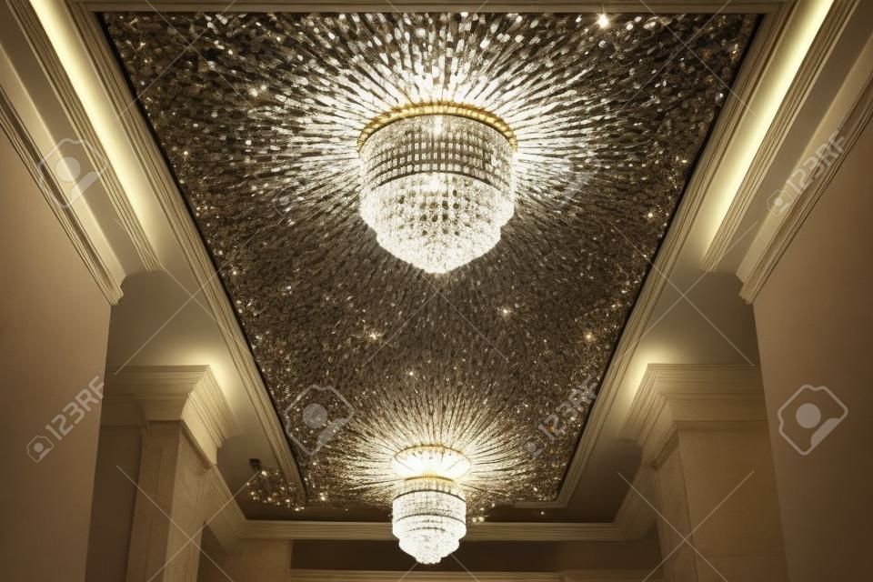 Close-up of a beautiful crystal chandelier. Round expensive classic chandelier with lights turned on beautifully illuminates the ceiling.