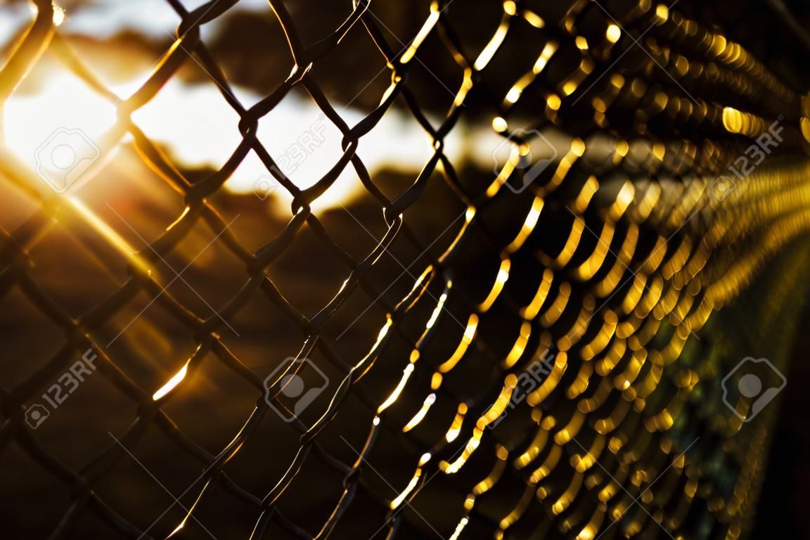 Texture d'un treillis géométrique, d'une clôture, d'un mur sur fond de ciel rouge au coucher du soleil. art abstrait. bokeh