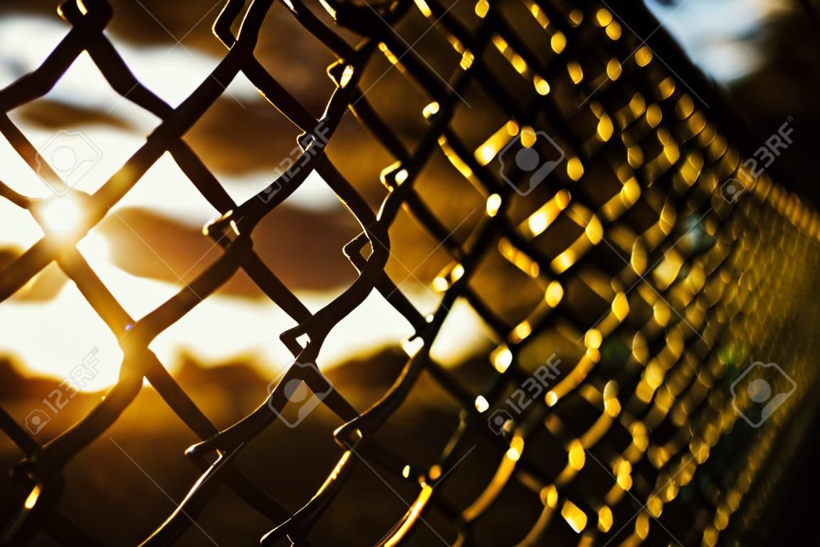 Texture d'un treillis géométrique, d'une clôture, d'un mur sur fond de ciel rouge au coucher du soleil. art abstrait. bokeh