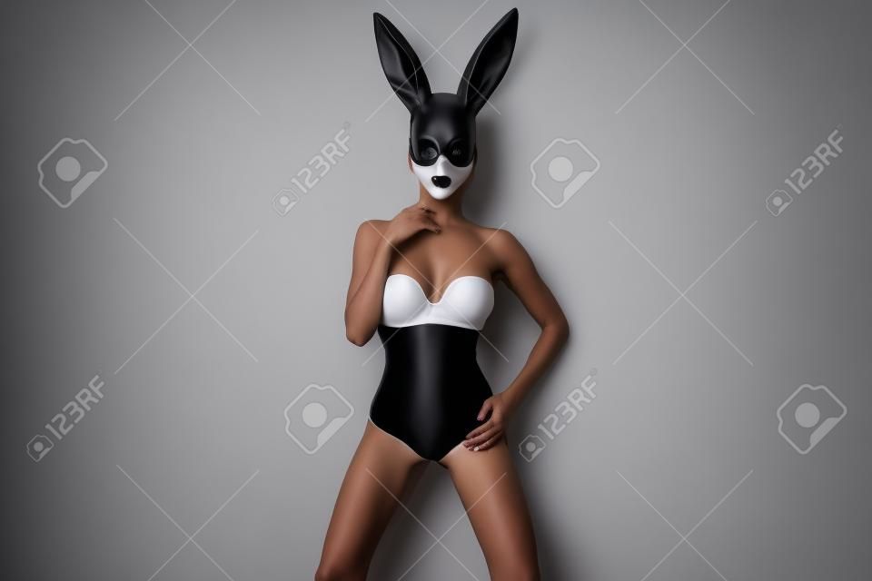 흰색 배경에 고립 된 검은 토끼 마스크에 여자. 마스크를 쓴 여성 모델.