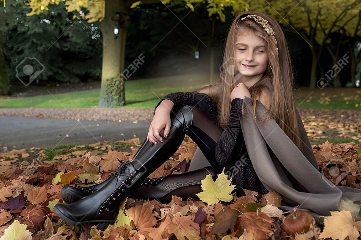 キッズファッション。秋の冬の服装の美しい少女は、公園、屋外で背景を残します。子供服。