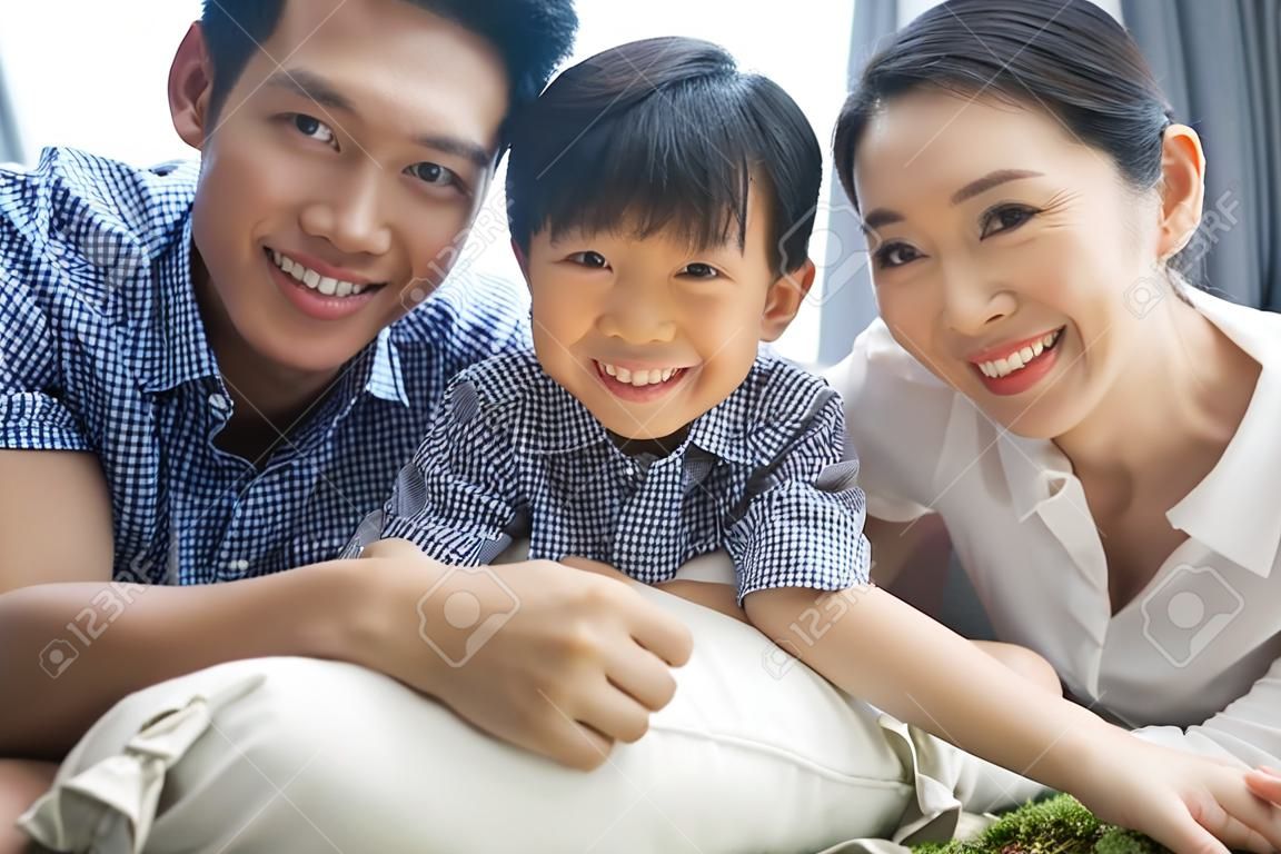 happy asian family spending time together on sofa in living room. family and home concept