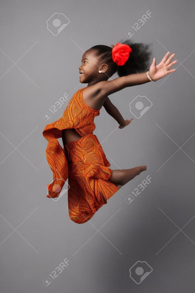 Ritratto di cute giovane ragazza asiatica africana saltando, su sfondo grigio