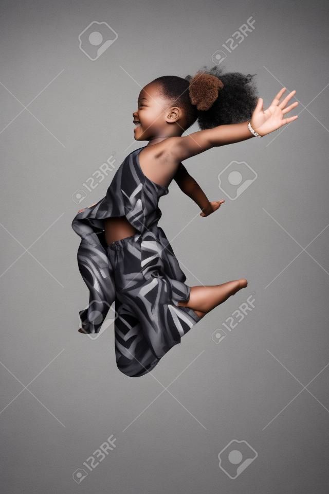 Ritratto di cute giovane ragazza asiatica africana saltando, su sfondo grigio