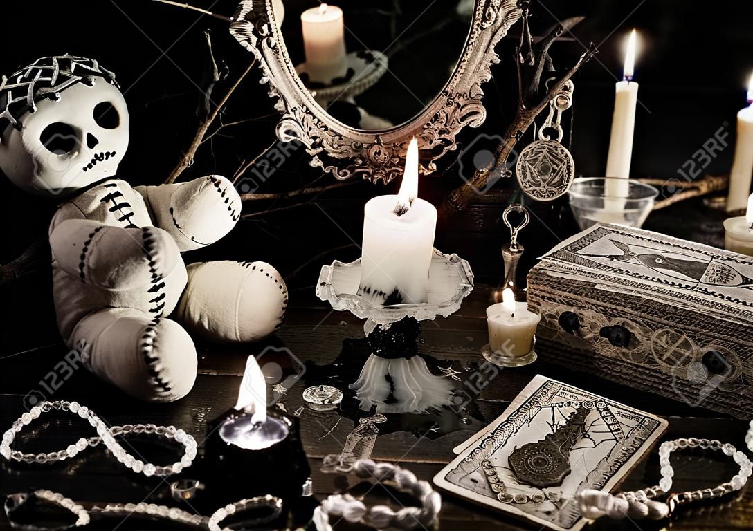 Zauberritual mit Voodoo-Puppe, Spiegel, böse Kerzen und Tarotkarten im Vintage-Grunge-Stil. Halloween-Konzept, mystisch oder Wahrsagerei Zauber mit okkulten und esoterischen Symbolen