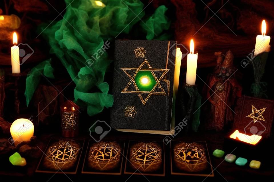 Creepy witch book with pentagram, tarot cards, runes, gemstone, candle and magic objects. Esoteric, wicca and occult background, fortune telling and divination ritual, mystic concept