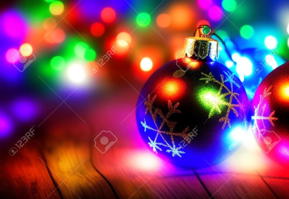 Christmas balls on a old plank with colorful lights background
