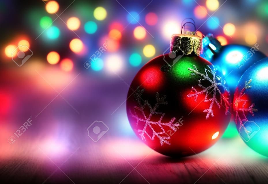 Christmas balls on a old plank with colorful lights background
