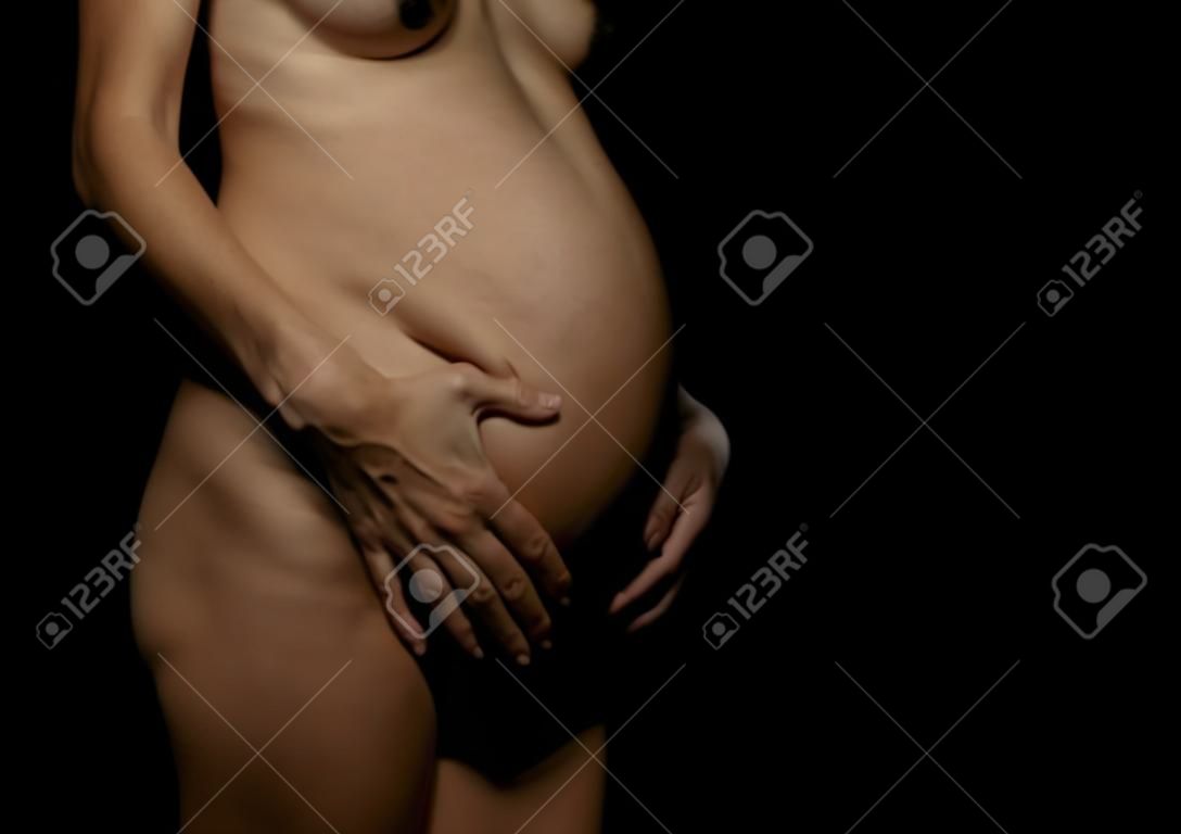 Bauch einer schwangeren Frau auf schwarzem Hintergrund