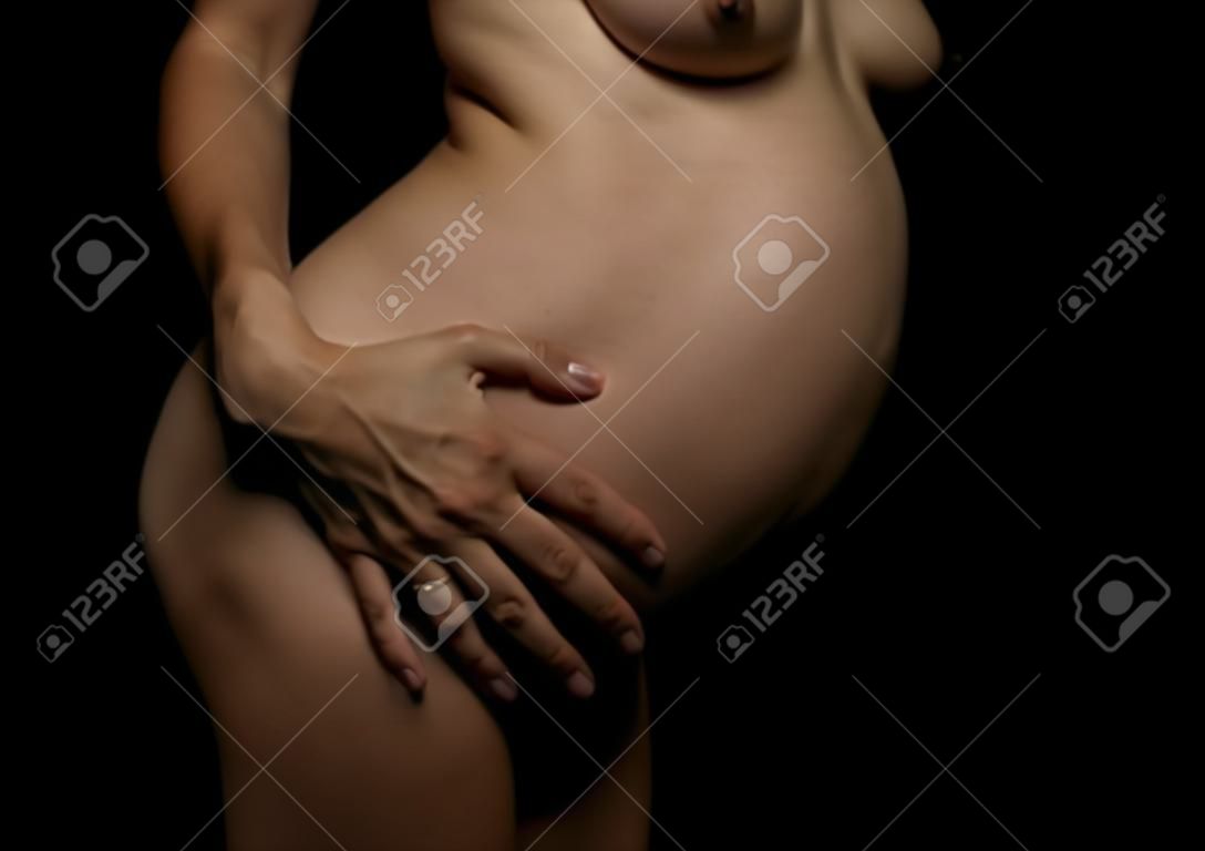 Bauch einer schwangeren Frau auf schwarzem Hintergrund