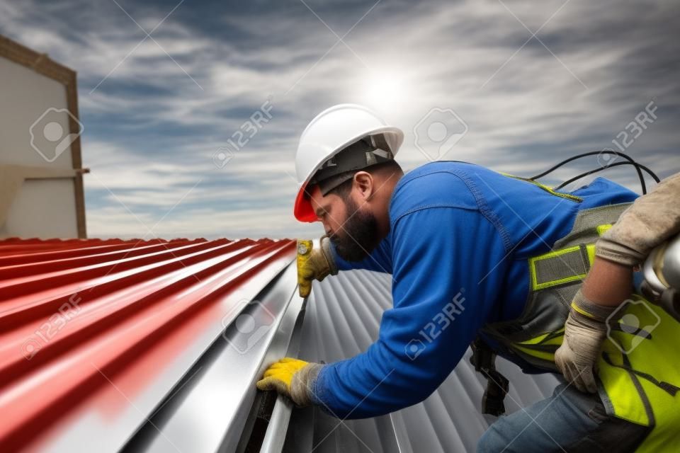 Roofer 건설 노동자는 새 지붕, 루핑 도구, 금속 시트가 있는 새 지붕에 사용되는 전기 드릴을 설치합니다.