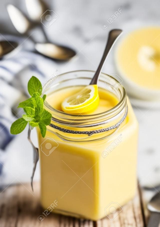 Ein Glas Lemon Curd mit einem Löffel