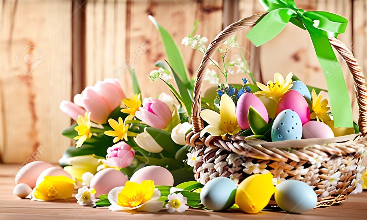 Composition de Pâques avec des fleurs de printemps et des oeufs de Pâques colorés dans le panier. Carte de Pâques avec espace de copie.