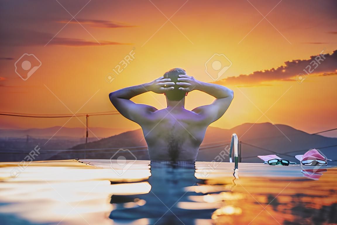 Un hombre relajarse en la piscina al atardecer, vacaciones de verano
