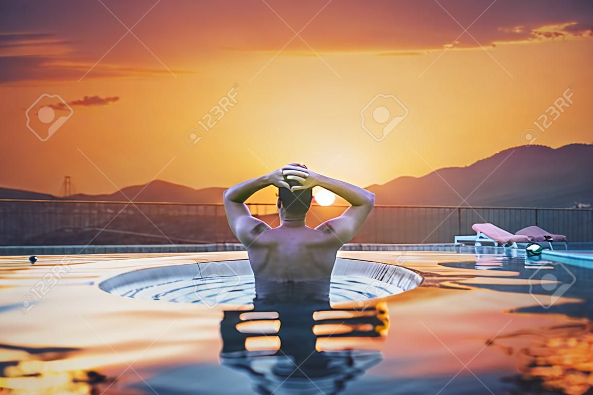 um homem relaxar na piscina no pôr do sol, férias de verão