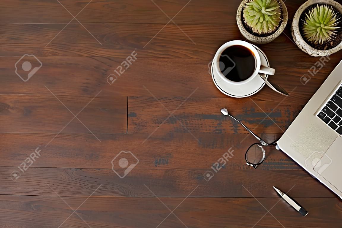 Image vintage de table en bois avec ordinateur portable, tasse de café et fournitures. Vue de dessus avec espace de copie, mise à plat.