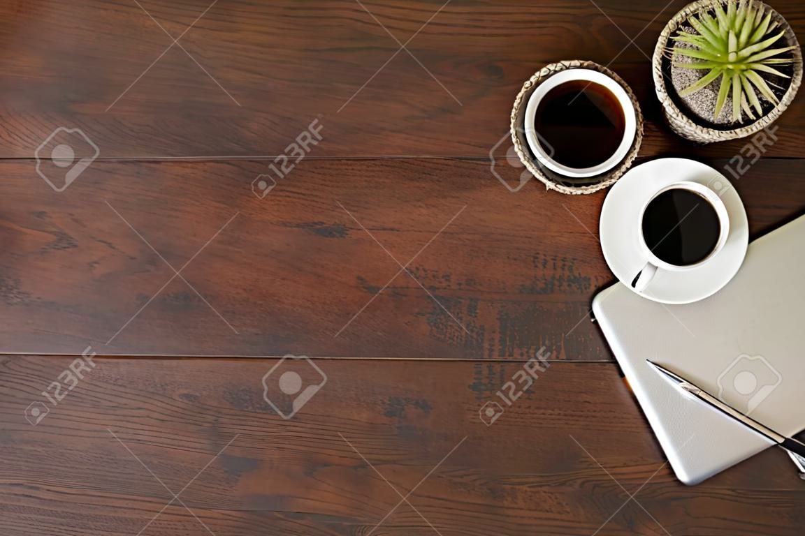 Vintage image of wood table with laptop computer, cup of coffee and supplies. Top view with copy space, flat lay.