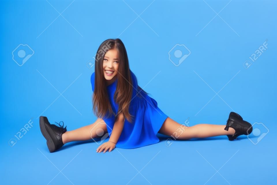 Beautiful girl sits on a splits. isolated on a blue background