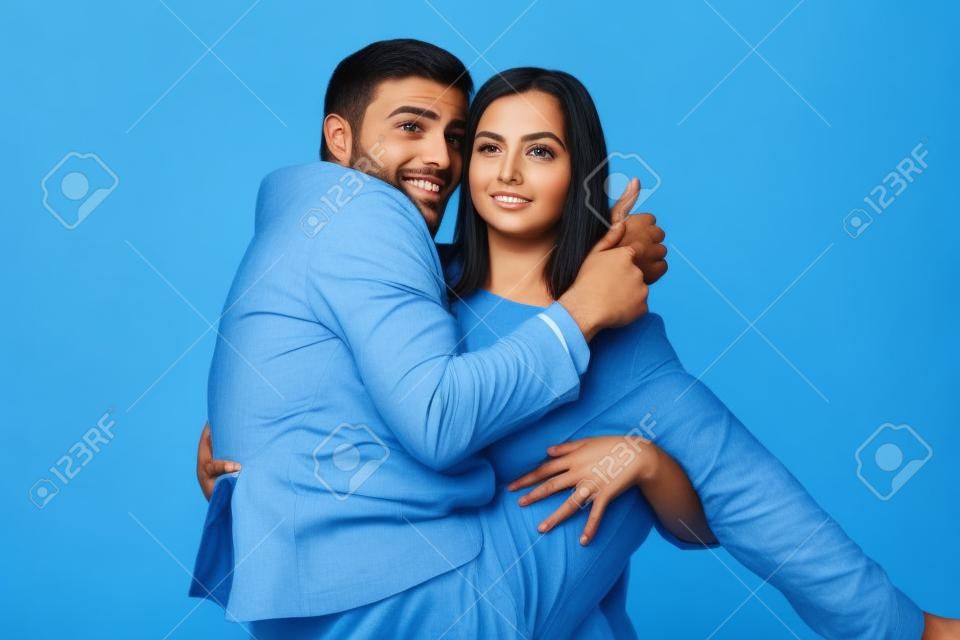 Family problems, responsibility, feminism and relationship concept - Woman carrying man in her arms on blue background