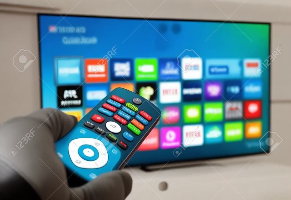 Smart tv and hand pressing remote control.
