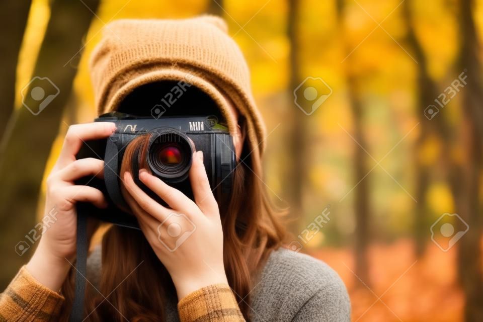 Persona con cámara en otoño. Una fotógrafa toma una foto de la hermosa naturaleza otoñal. escuela de fotografia