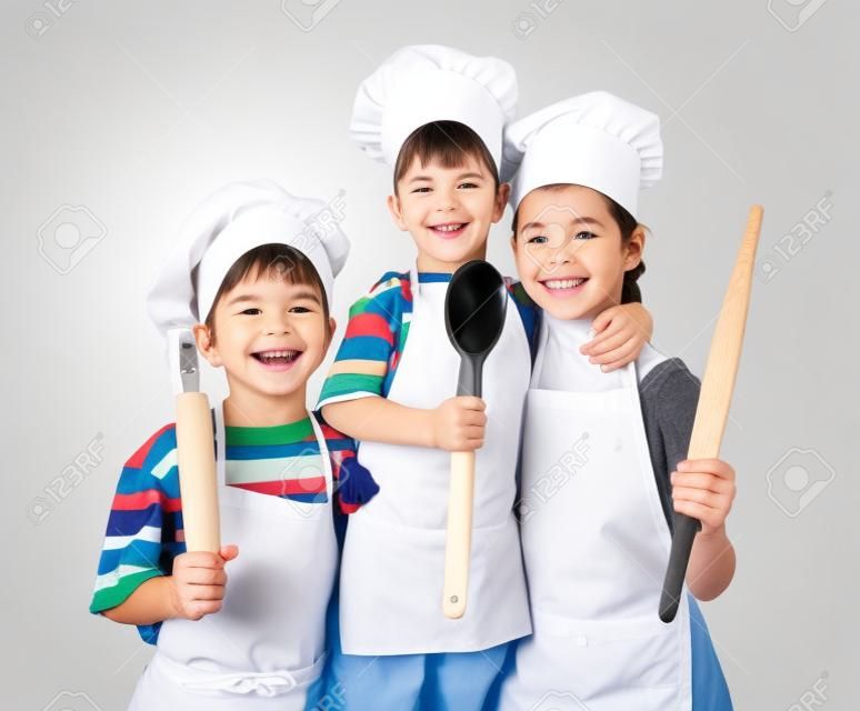 Drie kleine glimlachende chefs met lepel en rolspeld, geïsoleerd op wit