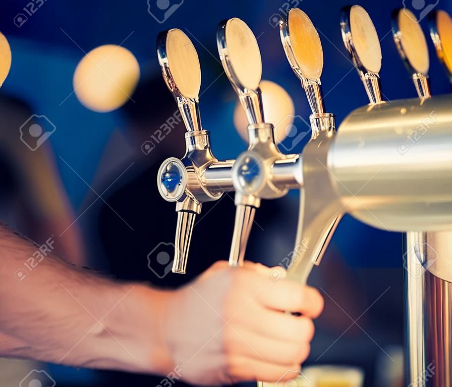 barman en la mano grifo de cerveza verter una cerveza lager de barril que sirve en un restaurante o bar.