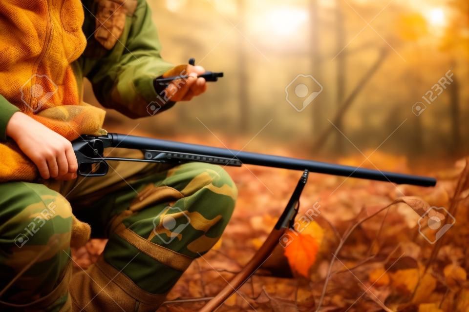 Hunter with hunting rifle in autumn forest