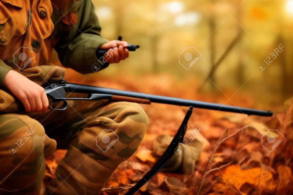 Hunter with hunting rifle in autumn forest
