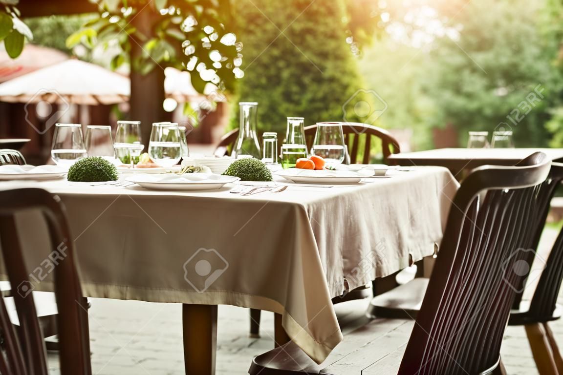 Ristorante di strada in estate. Sedie e tavolo in legno serviti con piatti